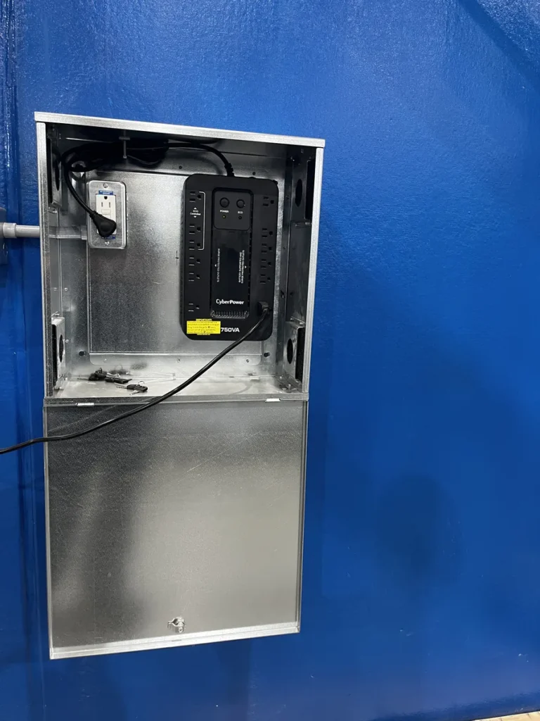 Open prototype electrical enclosure mounted on a blue workshop wall